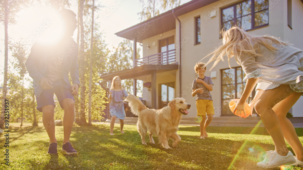 Beautiful Family of Four Play Catch Toy Ball with Happy Golden Retriever Dog on the Backyard Lawn. Idyllic Family Has Fun with Loyal Pedigree Dog Outdoors in Summer House Backyard.