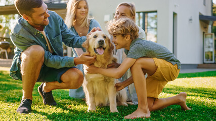 Wall Mural - Smiling Beautiful Family of Four Posing with Happy Golden Retriever Dog on the Backyard Lawn. Idyllic Family Cuddling Loyal Pedigree Dog Outdoors in Summer House Backyard.