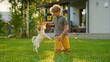 © Gorodenkoff - Cute Boy Plays with His Favourite Dog Friend while Having Picnic Outdoors on the Lawn. He Pets and Teases His Little Smooth Fox Terrier with His Favourite Toy. Idyllic Summer House.