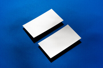 Two stacks of blank businesscards on blue background