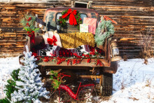 The Back Of A Rusty 1960s Truck Decorated With Christmas Ornaments With A Wood Plank Background In A Winter Landscape