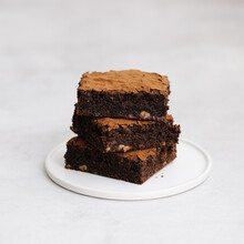 Stack Of Three Brownie Squares With Cocoa Powder