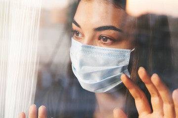 Woman wearing a mask looking out the window