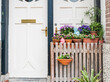 © Lawren Lu/Stocksy - White door with wooden gate and spring flowers