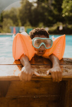 African American Boy In A Pool With Blue Diving Goggles And Orange Muffs