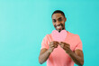 © Carlos David - Portrait of a smiling young man holding pink heart for romantic valentineÕs day isolated on blue copy space