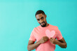 © Carlos David - Portrait of a serious  young man in love, holding pink heart for romantic valentineÕs day isolated on blue copy space