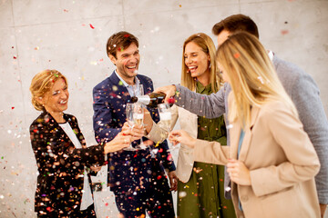 Wall Mural - Group of business people celebrating and toasting with confetti falling in the office