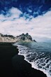Vestrahorn mountain in Iceland by the seas with waves rolling over a black sand beach