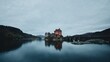 A moody view of Eilean Donan Castle with a reflection in the lake on a foggy day