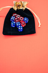 Canvas Print - Vertical shot of red and blue dice on a dice bag isolated on a light orange background