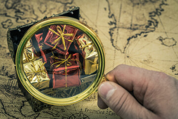 Aufkleber - The treasure hunt. Hand with a magnifying glass above a chest full of valuables and gifts