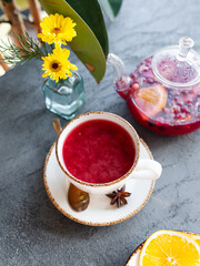 Wall Mural - white cup with red berry hot tea on a saucer on a gray background