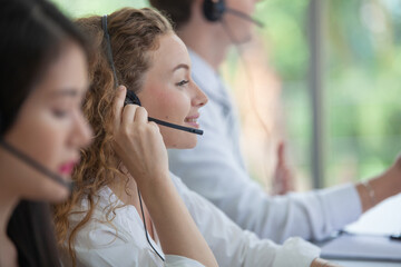 Wall Mural - Call center worker accompanied by her team. Asian woman working in call center office as a telemarketer, customer support operator at work