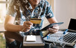 © NINENII - Male use credit cards to pay through tablet and laptop in office.