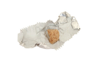 Closeup of a chewed gum on a crumpled foil bubblegum packaging isolated on white background