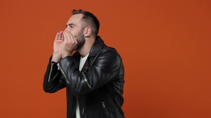 Wall Mural - Cheerful young bearded man 20s wearing casual black leather jacket posing isolated on orange color background in studio. People emotions lifestyle concept. Looking aside screaming with hands gesture