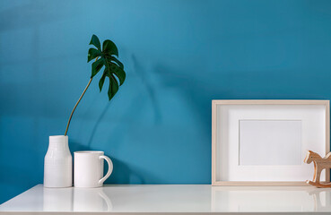 Mockup wooden frame and ceramic vase on white top table with light blue wall.