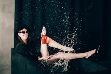 girl in a black jacket and hat posing in a black bath. bottle of wine