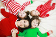 © alexkich - A family in striped pajamas is resting at home. Little children dressed as elves are lying on the sofa. Happy family.