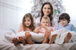 © alexkich - A family with children having fun on the bed under the covers during the Christmas holidays.