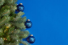 Christmas Blue Background With Christmas Tree Branch Decorated And Christmas Glass Blue Ball. Vertical Card
