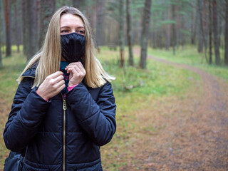 Beautiful european Women Wearing Protective Mask Outside Pretty young girl in medical black face mask in a forest. covid19 concept. modern reality. copy space. 2020, allergy. Autumn season. Copy space