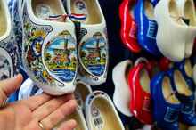 Kinderdijk, The Netherlands, August 2019. Souvenir Dutch Clogs, Produced In Different Shapes And Colors, Make A Good Show In The Display. The Tourist's Hand Touches Them To Observe Them.