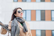 © Iulia - woman in sun glasses and coat standing in atumn city