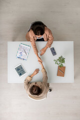 Poster - Top view of two elegant businesswomen shaking hands over desk after negotiating