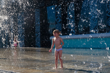 A little girl splashes water from a fountain on the territory of the Moscow city