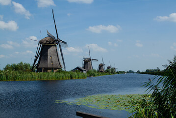 Wall Mural - Kinderdijk, The Netherlands, August 2019. On a beautiful summer day the typical landscape of the place: historic windmills, in perfect condition, in the Dutch countryside furrowed by canals .