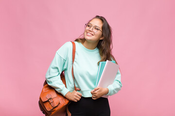 young hispanic woman smiling happily and daydreaming or doubting, looking to the side