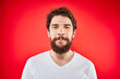 © SHOTPRIME STUDIO - Bearded man fun emotions lifestyle cropped view white t-shirt red background
