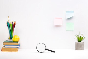 Wall Mural - side view for workspace with education supply on it over grey wall background. magnifying glass and stationery and books on a table top. education and study concept