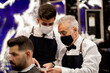 © Alberto Cotilla - A young barber talks to his co-worker while looking at a bill