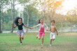 © rachaphak - Group of young children happily  holding hands and running towards camera in park.