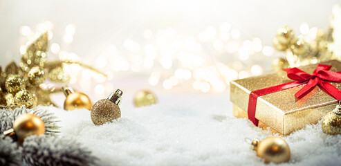 christmas gold decorations on snow with fir tree branches and christmas lights. winter decoration ba