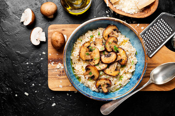 Wall Mural - Risotto with brown champignon mushrooms on black stone background. top view