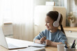 © fizkes - Smiling little girl wearing headphones using laptop, studying online, looking at computer screen, positive child schoolgirl watching webinar, listening to lecture, homeschooling concept