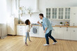 © fizkes - Happy young father and little African American girl playing funny game, standing in kitchen, dad and adorable daughter holding kitchenware as microphones, singing, multiracial family having fun