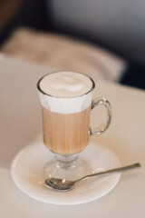 Wall Mural - A Glass of hot cappuccino coffee on the table in cafe shop with breakfast background. vintage film color tone.