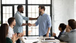 Perfect job. Friendly african american boss or team leader shaking hand of happy excited caucasian employee manager worker on staff meeting at boardroom demonstrating respect greeting with promotion