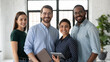 © fizkes - Portrait of successful diverse international business team friendly group of four coworkers capable reliable professional specialists posing at office standing close together smiling looking at camera