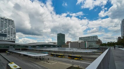 Wall Mural - Utrecht, Netherlands - June 12 2020: 4k time lapse of the Utrecht central station with busses and trains arriving and departing on a sunny day with thick white clouds rolling by