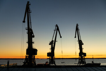 Aufkleber - silhouettes of cranes in the port in the evening at sunset