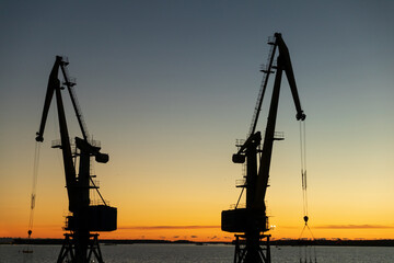 Aufkleber - silhouettes of cranes in the port in the evening at sunset