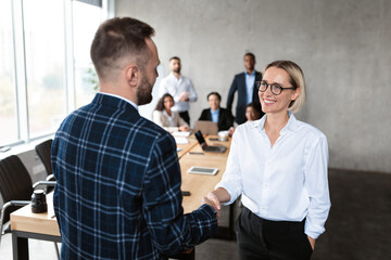 Wall Mural - Businessman Shaking Hands With Businesswoman During Corporate Meeting In Office