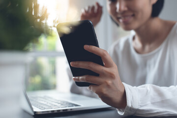 Poster - Young asian woman making facetime video calling on mobile phone during working on laptop computer at home office