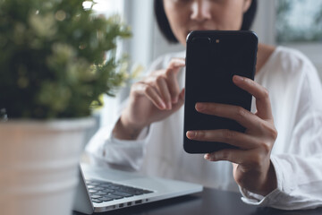 Poster - Woman using mobile phone during working on laptop computer from home office